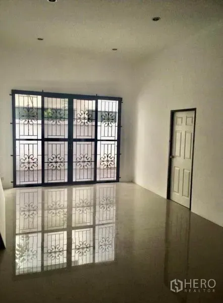 Townhouse for rent in Wang Thonglang, Bangkok - Bright room with glossy tile floor and large window featuring ornate security grilles.