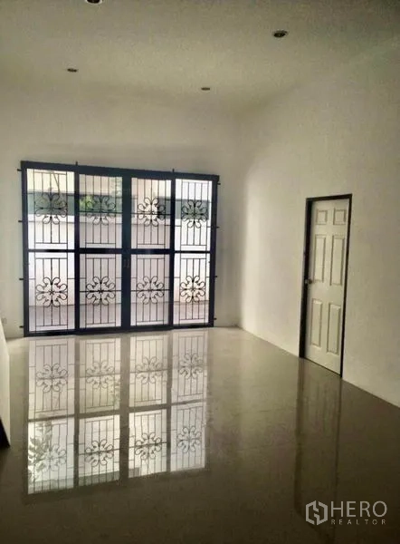 Townhouse for rent in Wang Thonglang, Bangkok - Bright room with glossy tile floor and large window featuring ornate security grilles.