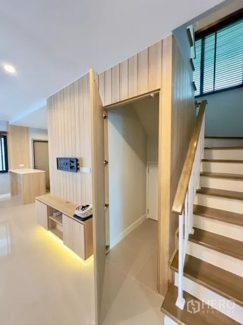 Detached House for rent in Samut Prakan - Staircase with under-stairs storage, wood wall paneling and built-in media console.