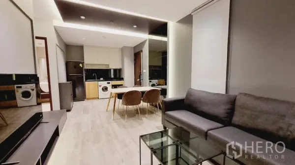 公寓 出售在Watthana, Bangkok - 开放式客厅连接小厨房与餐区，灯光温暖。