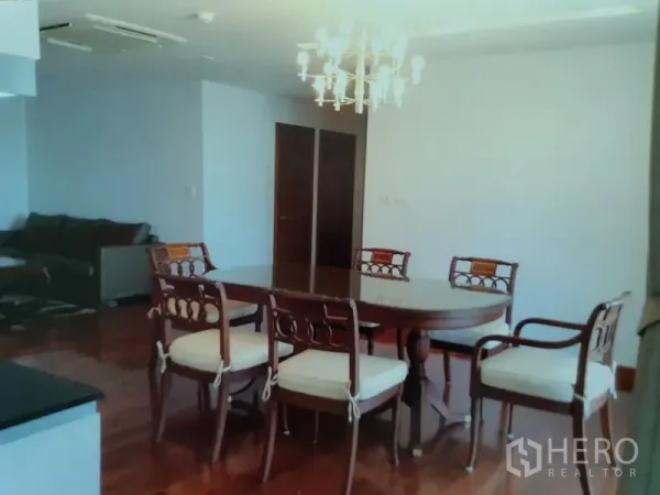 公寓 出租在Watthana, Bangkok - 明亮的餐区，椭圆木餐桌与枝形吊灯，实木地板，旁连客厅。