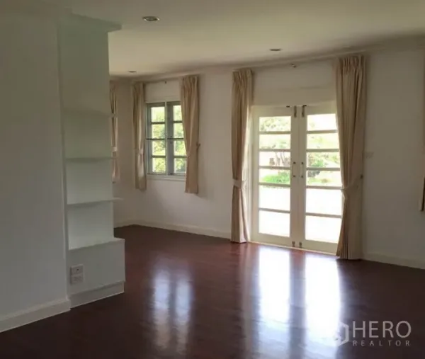 独立式住宅 出租在Bang Phli, Samut Prakan - 采光充足的客厅，木地板，法式门与窗帘。