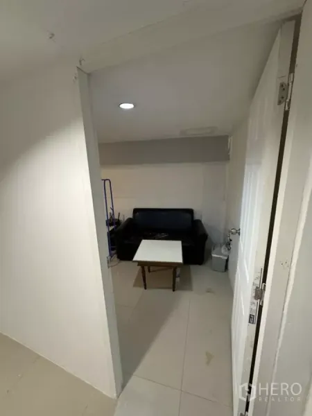 พื้นที่ขายปลีก ให้เช่า - ห้องด้านหลังขนาดกะทัดรัด มีโซฟาหนังสีดำ โต๊ะกลาง และไฟฝังฝ้า