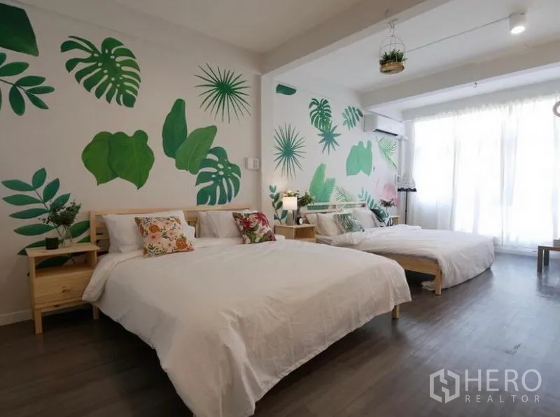 Townhouse for rent in Khlong Toei, Bangkok - Large bedroom with two double beds, tropical leaf mural, wood flooring and full-height windows with curtains.