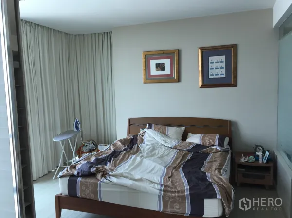 คอนโด ให้เช่าในWatthana, Bangkok - ห้องนอนคอนโด 1 ห้องนอน เขตวัฒนา เตียงไม้ โต๊ะข้างเตียง ภาพแขวนผนัง และผ้าม่านเต็มบาน