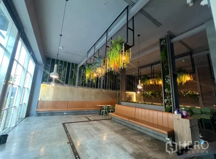 零售空间 出租 - 宽敞餐厅大厅，水泥地面、卡座与垂吊植物。
