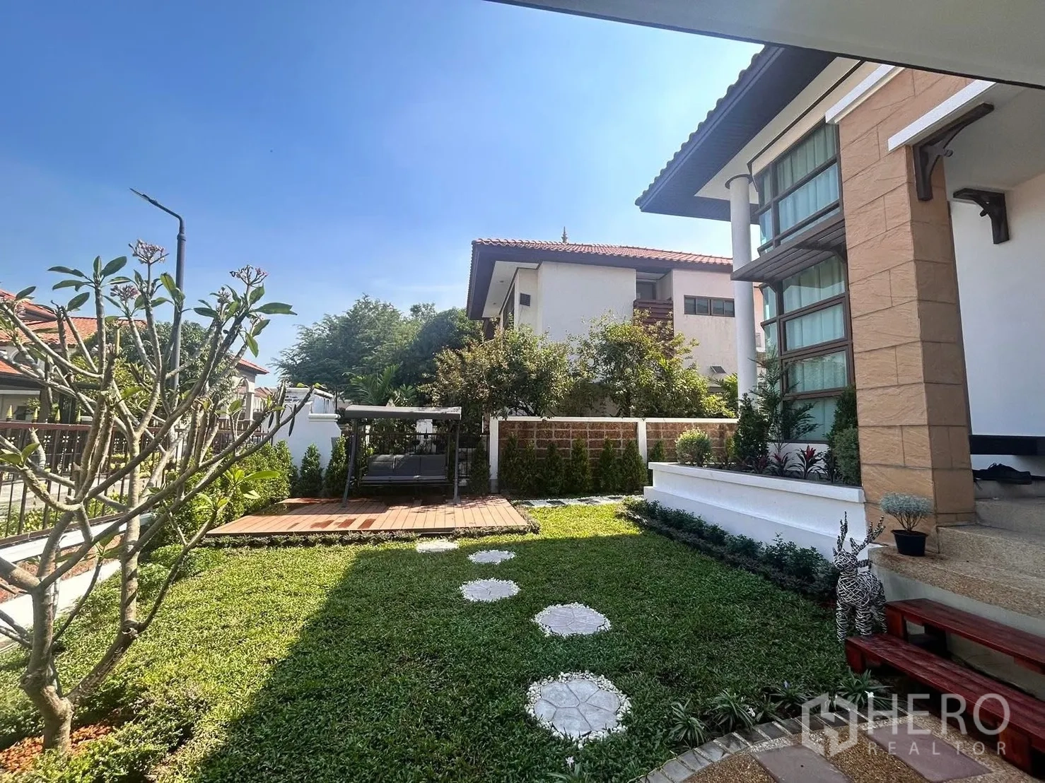 บ้าน ให้เช่าในLat Krabang, Bangkok - สนามหญ้าหน้าบ้านพร้อมชานไม้ชิงช้า และตัวบ้านสไตล์โมเดิร์น