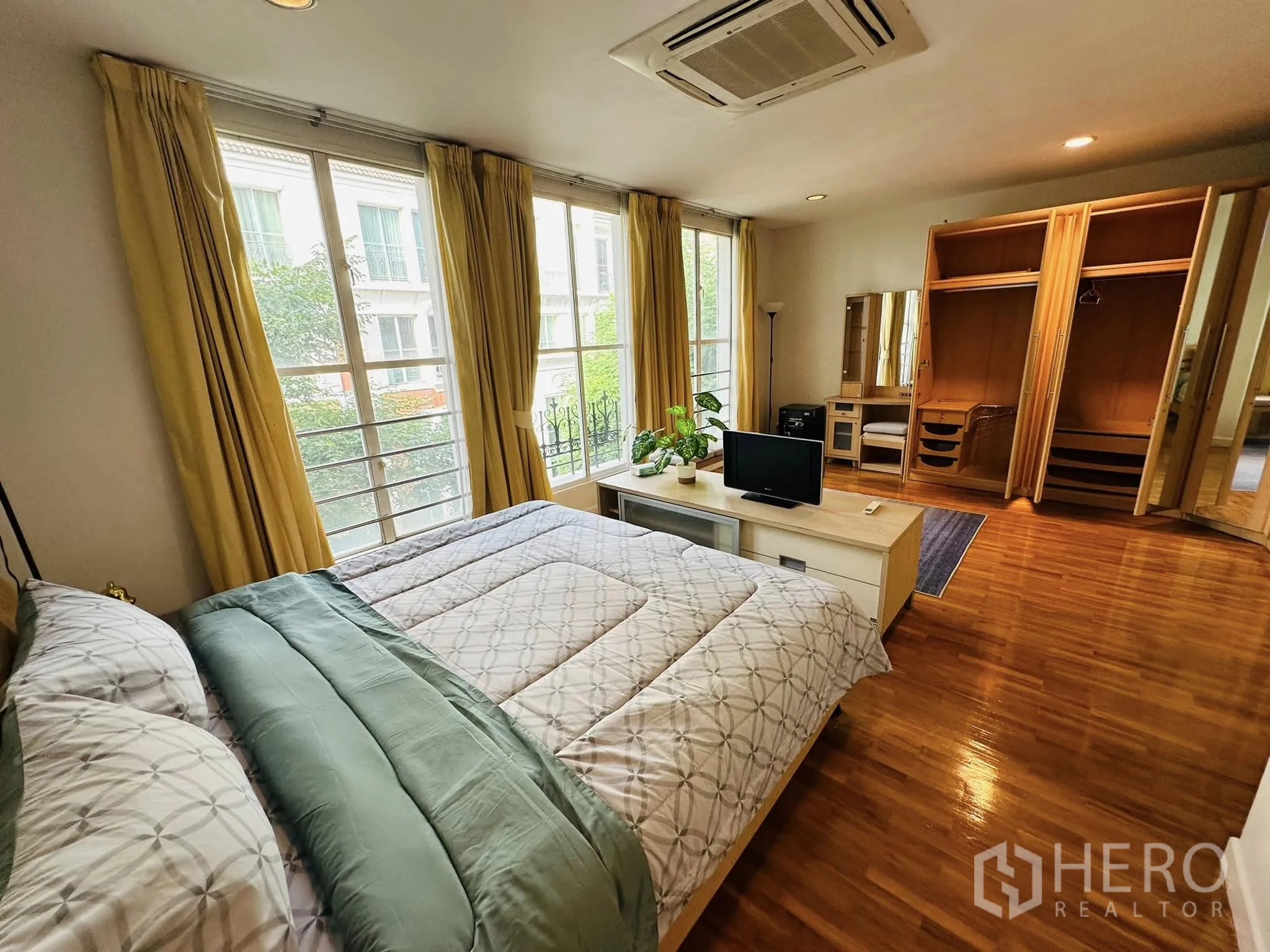 Townhouse for rent in Watthana, Bangkok - Bedroom with ceiling cassette air-conditioner, open wardrobes, big windows and glossy wood floor.