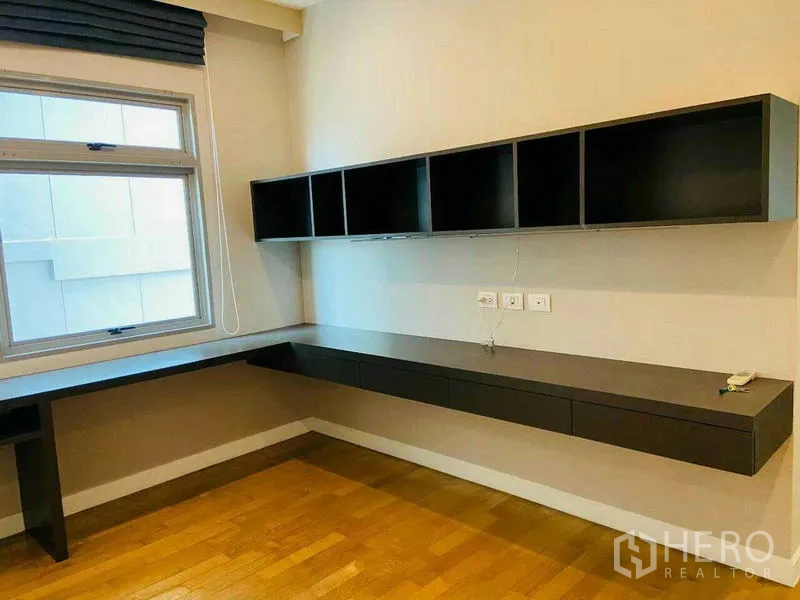 Condominium for rent in Watthana, Bangkok - Built-in home office with a long floating desk and wall cabinets beside a window.