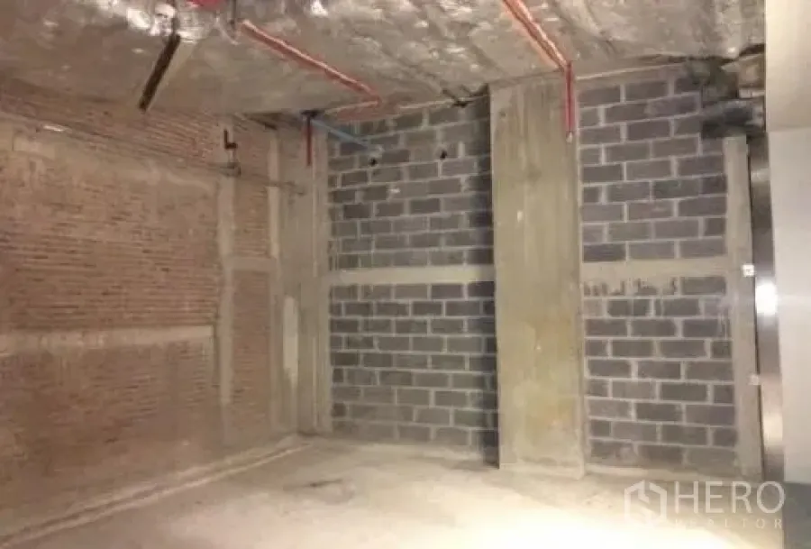 零售空间 出租 - 76平米毛坯零售单元，外露混凝土顶与砖块墙体，可见红色管线。