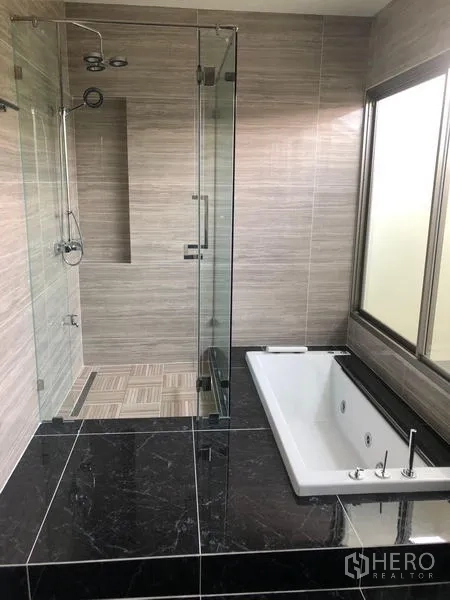 Detached House for rent in Bang Phli, Samut Prakan - Contemporary bathroom with a glass-enclosed rain shower and built-in bathtub over dark stone.
