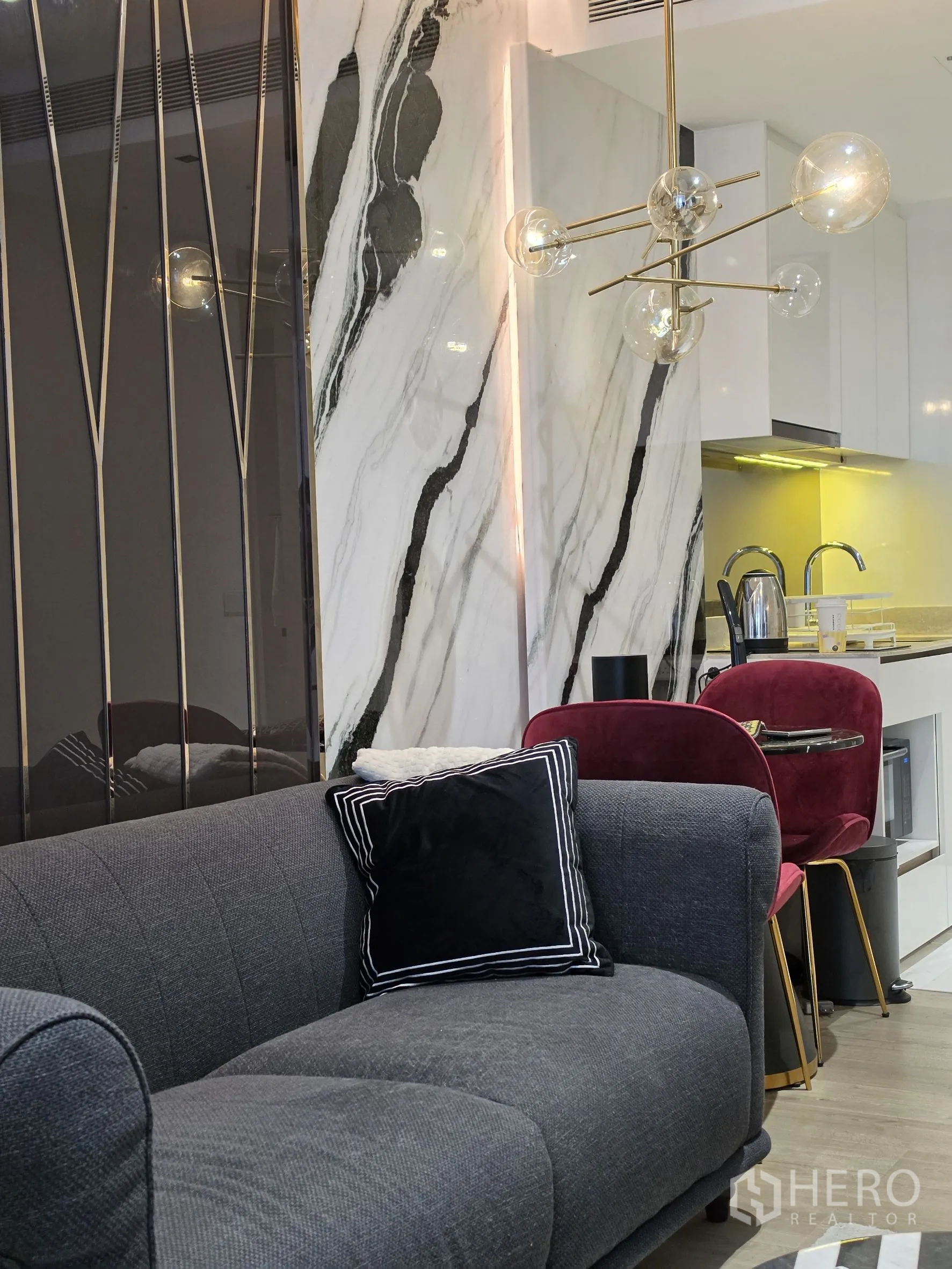 คอนโด for rent in Khlong Toei, Bangkok - ห้องนั่งเล่นอบอุ่นมีโซฟาสีเทา ผนังลายหินอ่อน และโคมไฟแขวนสไตล์โมเดิร์นเหนือชุดทานข้าว
