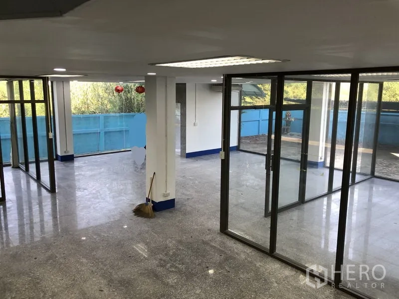 Warehouse for rent in Sai Mai, Bangkok - Ground-floor showroom or office with glass walls opening to a terrace area.