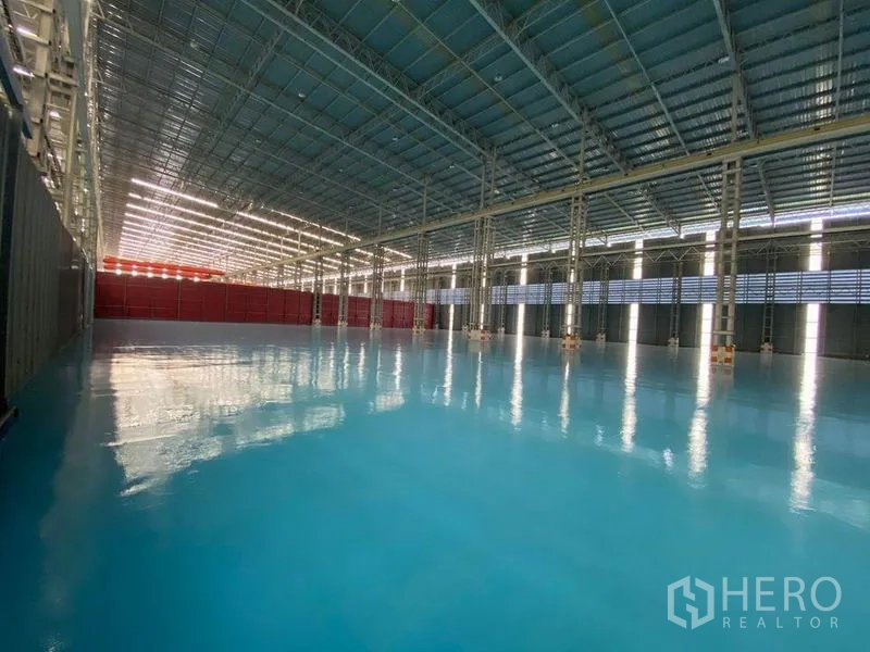 Factory for rent in Khlong Toei, Bangkok - Expansive production space with polished blue epoxy floor and a red partition wall.