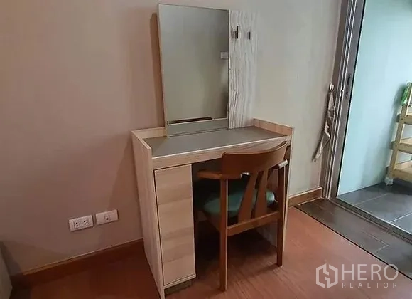 Condominium for rent in Huai Khwang, Bangkok - Bedroom corner with vanity table, mirror and chair next to the balcony door.