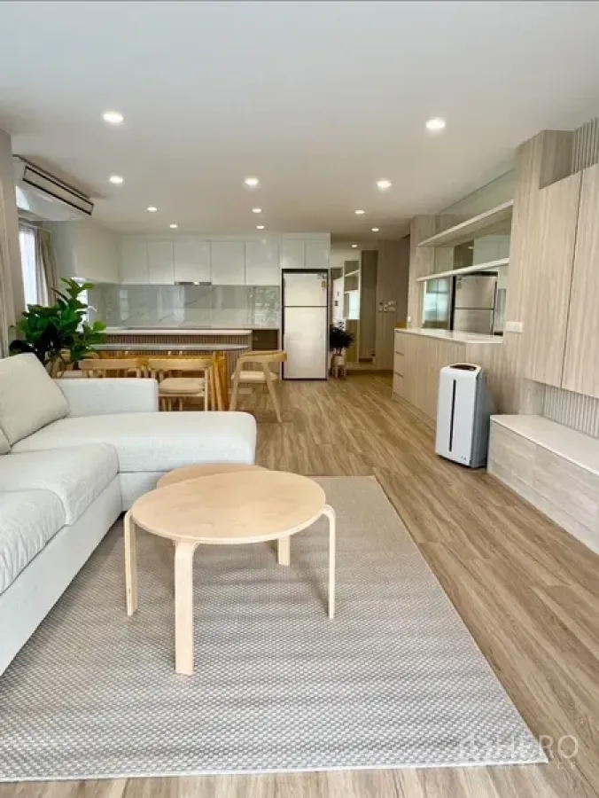 บ้าน ให้เช่าในBang Rak, Bangkok - ห้องนั่งเล่นแบบโอเพนสเปซ พื้นไม้ โซฟา และครัวสีขาวสว่าง