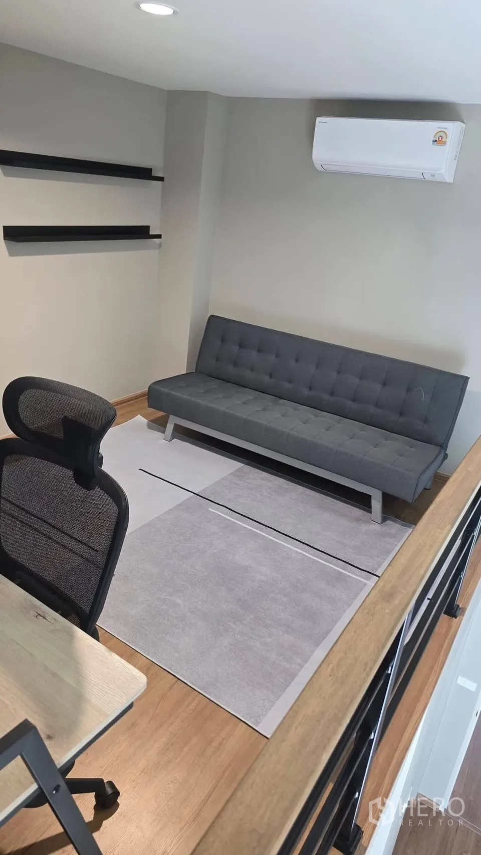 Townhouse for rent in Bang Phli, Samut Prakan - Loft-style home office with desk and gray sofa under air conditioner.