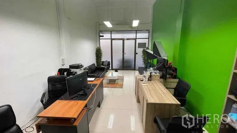 店屋 出租在Khlong Toei, Bangkok - 一层开放式办公区，设有工位、沙发与玻璃临街门面。