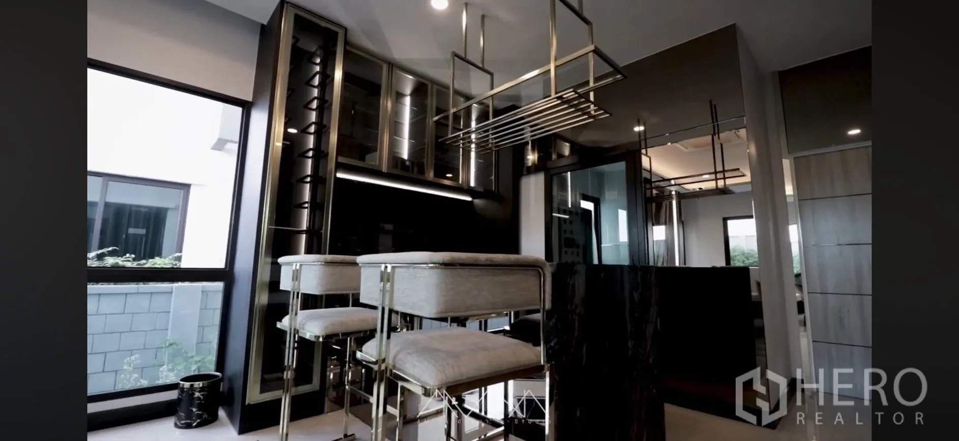 Detached House for rent in Saphan Sung, Bangkok - Modern bar with high stools, hanging racks, and glass cabinetry by a window.