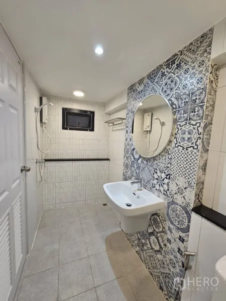 店屋 出租 - 卫生间配淋浴与热水器，白色瓷砖和圆镜。