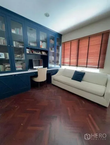 Townhouse for rent or sale in Bueng Kum, Bangkok - Upstairs study featuring blue built-in desk and shelves, herringbone wood floor, and a sofa.