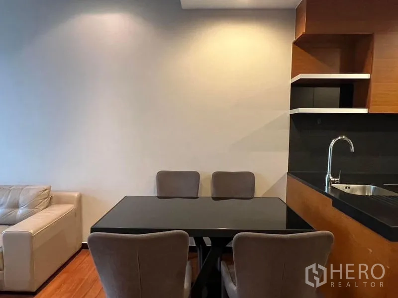 คอนโด ให้เช่า - มุมทานอาหาร โต๊ะท็อปกระจกสีดำกับเก้าอี้บุนวมสี่ตัว ข้างโซนครัว