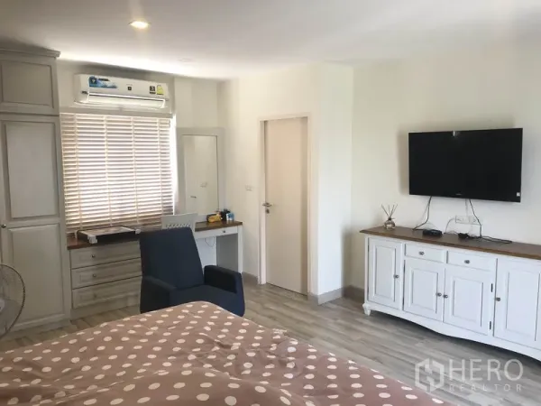 Townhouse for rent or sale in Saphan Sung, Bangkok - Spacious bedroom featuring a work desk, wardrobe, air conditioning, and wall-mounted TV.