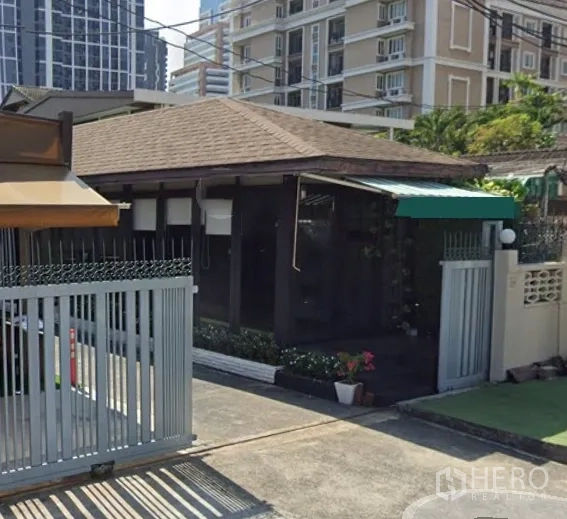 零售空间 出租在Watthana, Bangkok - 带大门的商铺，坡屋顶与雨篷，周边为高楼社区。