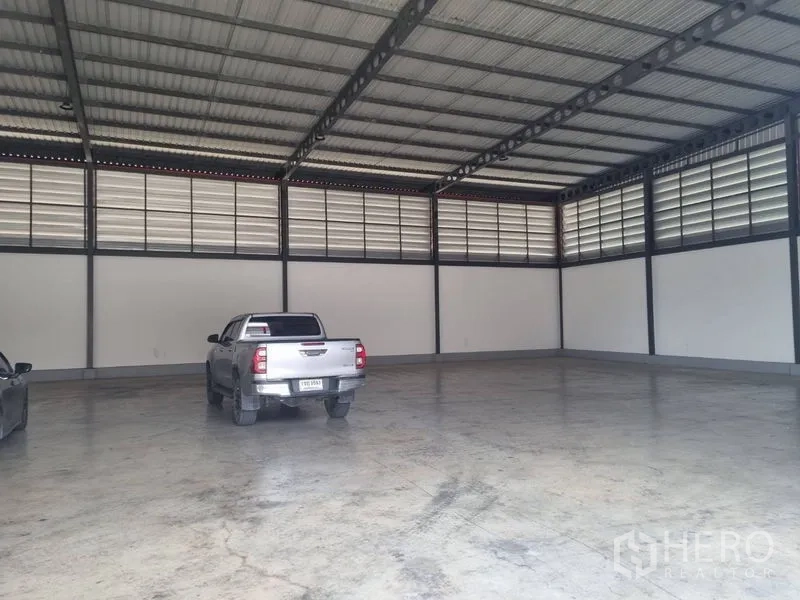 Warehouse for rent or sale in Krathum Baen, Samut Sakhon - Large high-ceiling warehouse interior with steel truss roof, ventilation louvers and concrete floor.