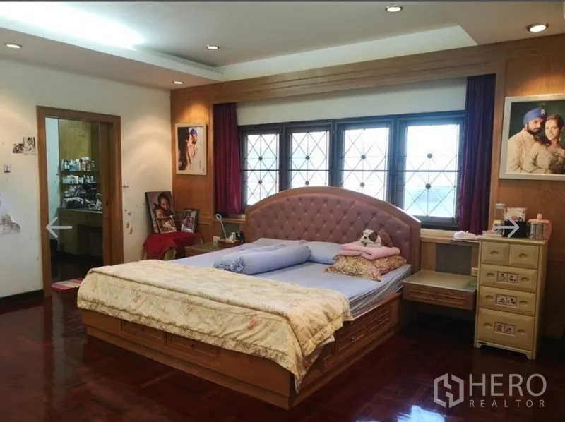 Detached House for sale in Khlong San, Bangkok - Master bedroom with upholstered headboard, wood accents and an ensuite door.
