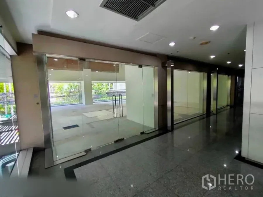 零售空间 出租在Khlong Toei, Bangkok - 商场走廊与一排玻璃店面，靠近该铺位。