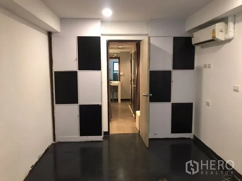 Home Office for rent or sale in Khlong Toei, Bangkok - Air-conditioned room with checkerboard wall panels and doorway toward a wash area.