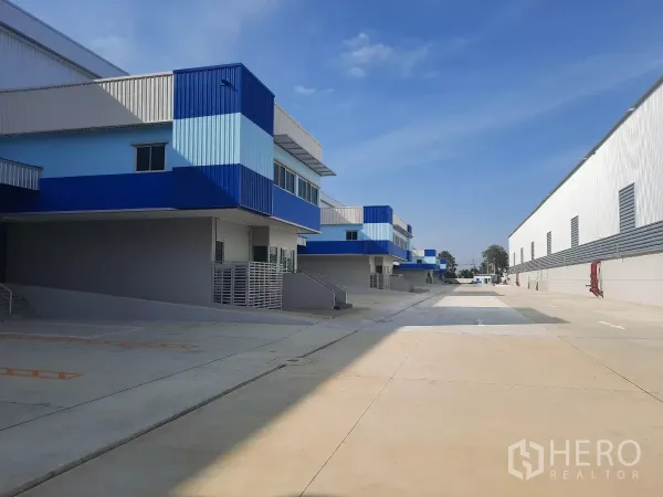 Factory for rent in Bang Lamung, Chon Buri - Row of blue-and-white factory units along wide truck-friendly driveway.