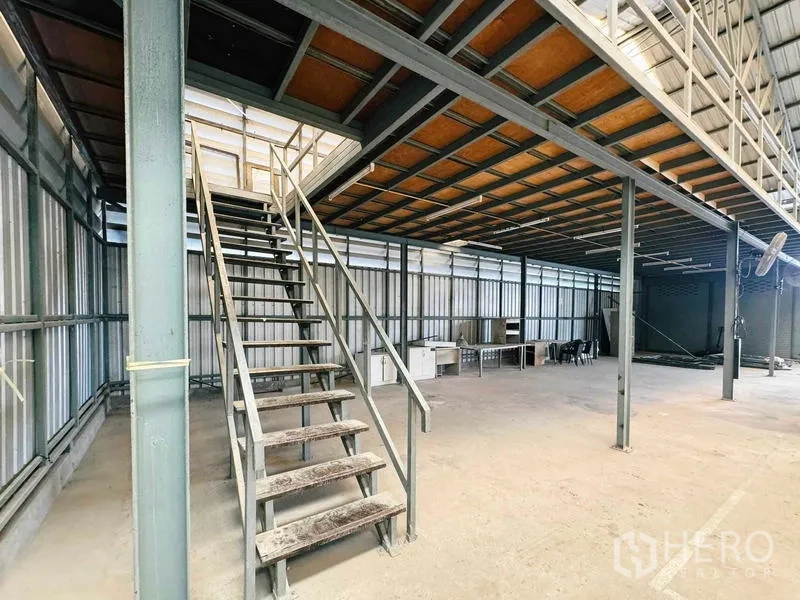 Warehouse for rent in Din Daeng, Bangkok - Metal staircase leading to the mezzanine beneath a steel truss roof.