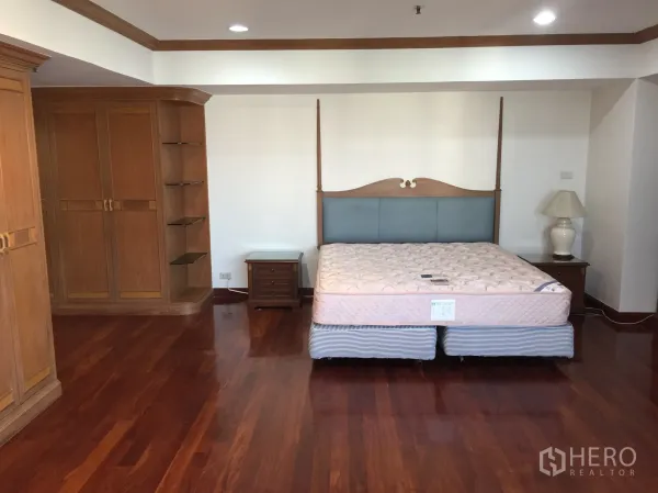 Condominium for rent in Watthana, Bangkok - Spacious master bedroom with polished hardwood floors and built-in wooden wardrobes.