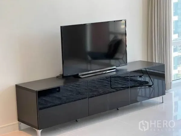 คอนโด ให้เช่าในWatthana, Bangkok - มุมทีวีบนตู้สีดำเงา ในห้องนั่งเล่นติดหน้าต่างสูงจรดเพดาน