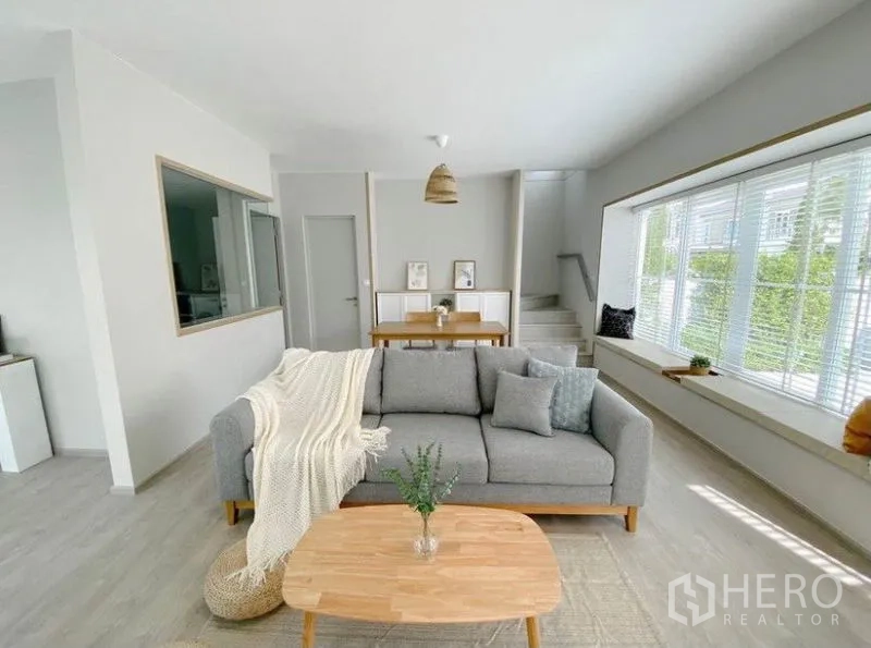 独立式住宅 出租在Prawet, Bangkok - 温馨客厅，超大景观窗与通往二层的楼梯