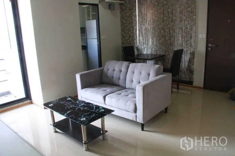 คอนโด ให้เช่าในPhaya Thai, Bangkok - ห้องนั่งเล่นสว่าง โซฟาสีเทา โต๊ะกลางลายหินอ่อน มุมทานอาหาร และประตูกระจกออกระเบียง