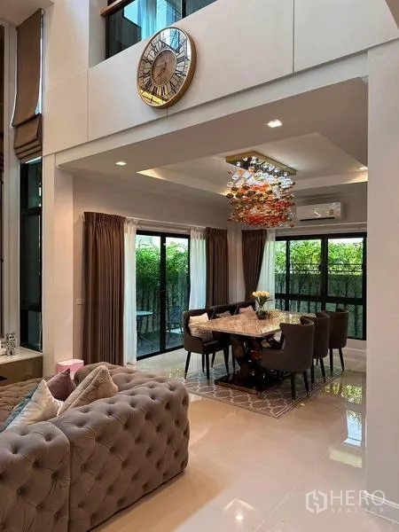 独立式住宅 出租在Prawet, Bangkok - 开放式餐区，艺术吊灯与通向绿篱的推拉门。