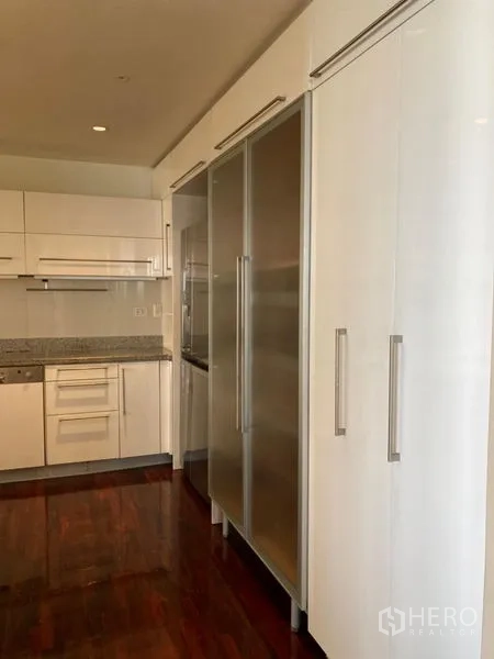 Condominium for rent in Bang Rak, Bangkok - Sleek kitchen cabinetry with tall frosted doors and integrated appliances.