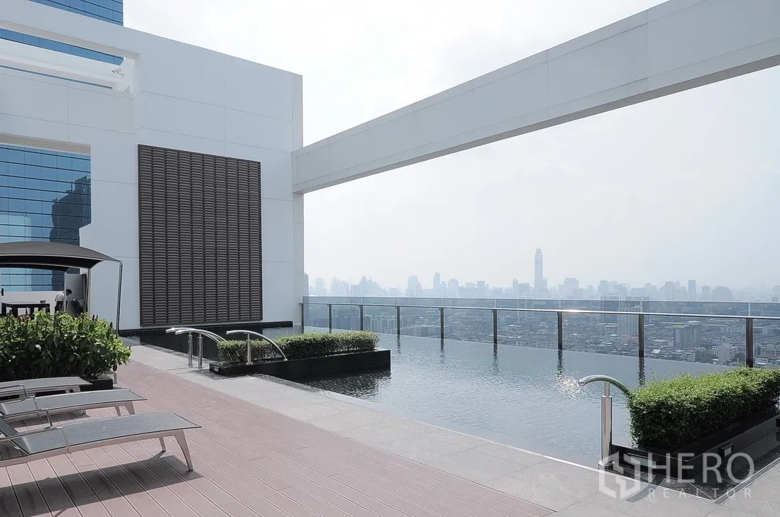 公寓 出售在Huai Khwang, Bangkok - 屋顶无边泳池，躺椅与城市广角景观。