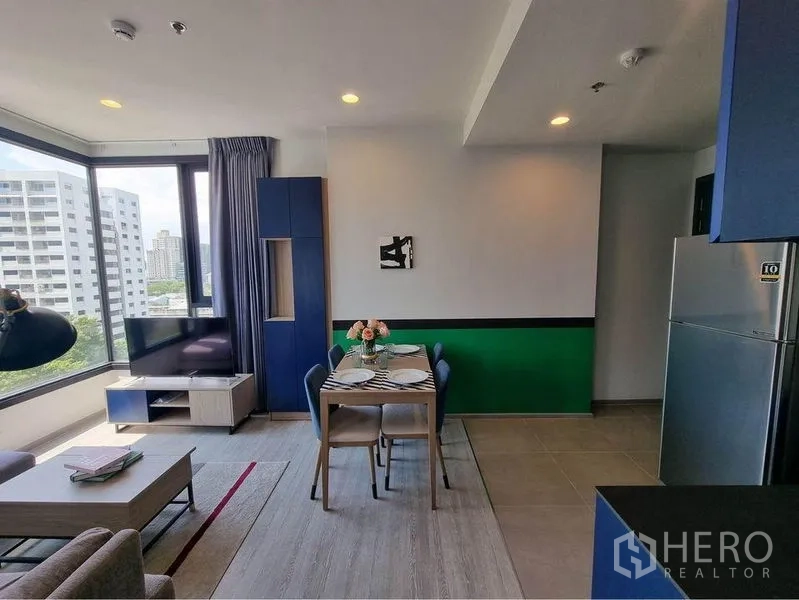 公寓 出租在Watthana, Bangkok - 采光充足的客餐厅，大窗、电视柜与四人餐桌，可赏城市景观。