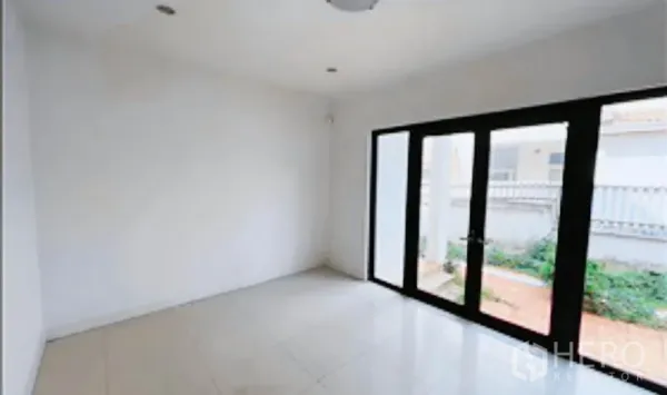 独立式住宅 出售在Khan Na Yao, Bangkok - 白色瓷砖多功能房，黑框落地玻璃门通往侧院