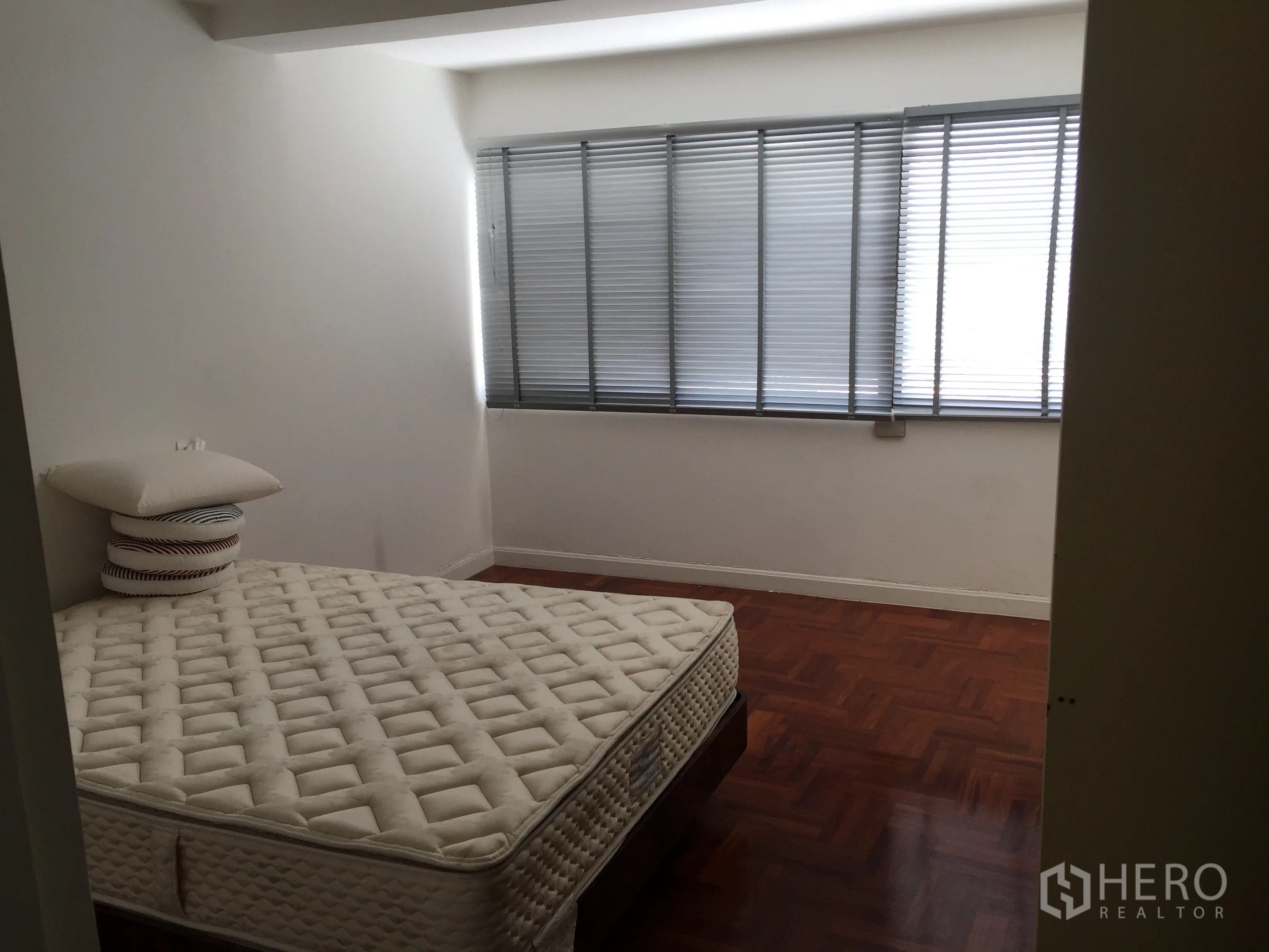 Condominium for rent in Sathon, Bangkok - Bedroom with large window and blinds, mattress on polished parquet floor providing natural light.