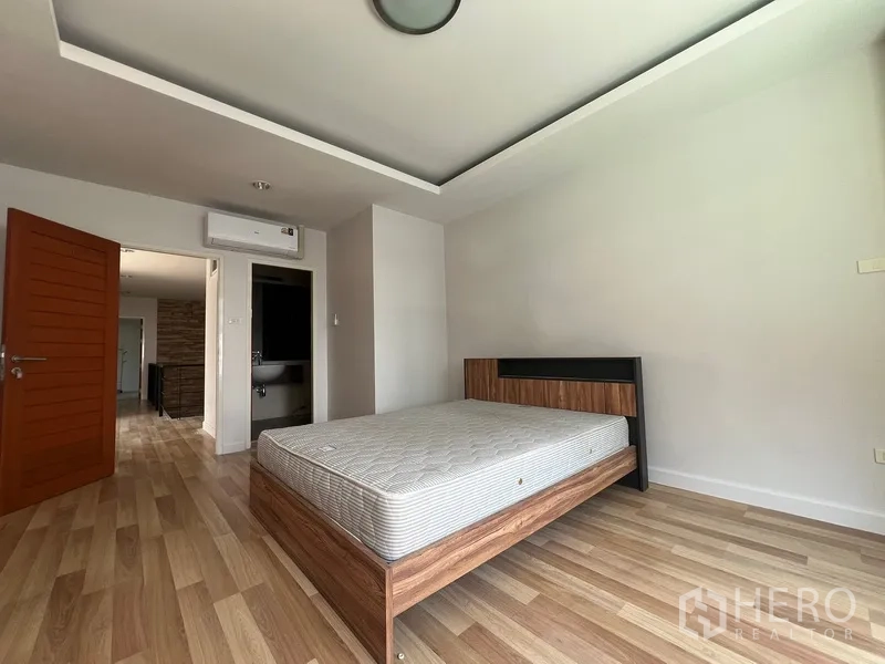 Townhouse for rent in Din Daeng, Bangkok - Secondary bedroom with bed, air conditioning and light wood floors.