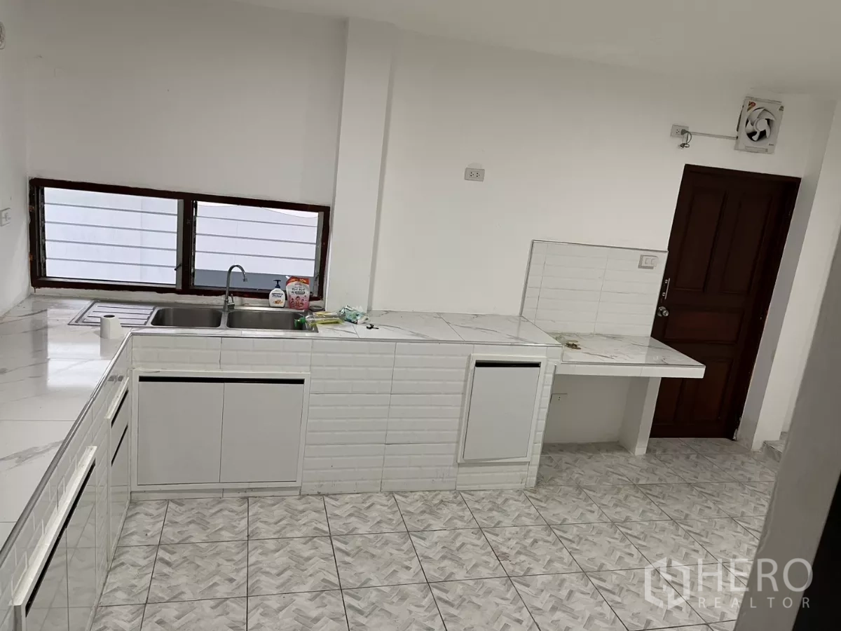 บ้าน ให้เช่าในWatthana, Bangkok - ห้องครัวสว่าง ตู้สีขาว เคาน์เตอร์ลายหินอ่อน อ่างล้างจานสองหลุม และพื้นกระเบื้อง.