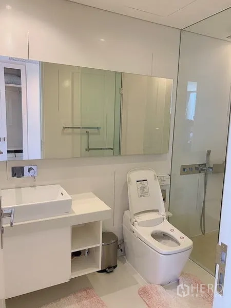 公寓 出售 - 明亮浴室，悬空洗手台、大镜柜、智能马桶与玻璃淋浴间。