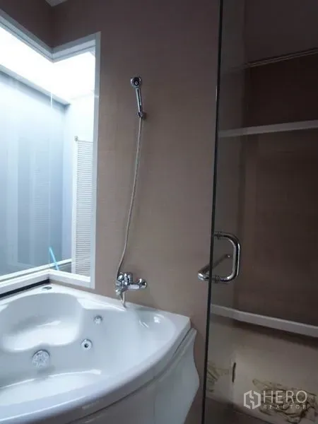 公寓 出租在Chatuchak, Bangkok - 浴室设转角按摩浴缸与玻璃淋浴间，旁有磨砂窗。