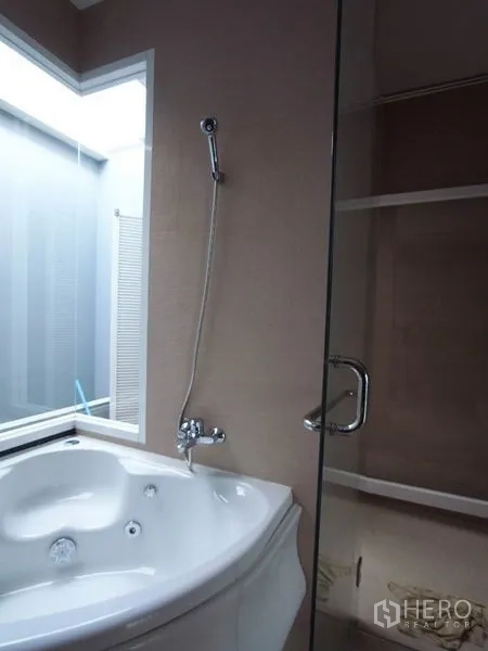 公寓 出租在Chatuchak, Bangkok - 浴室设转角按摩浴缸与玻璃淋浴间，旁有磨砂窗。