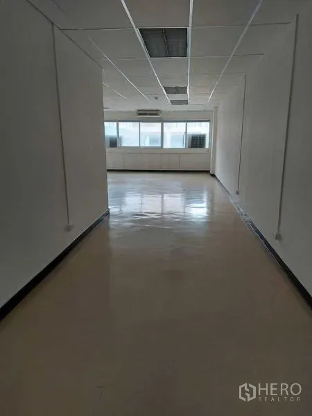 办公空间 出租在Pathum Wan, Bangkok - 开放式长形办公区，地面光洁，白色墙面，尽头为采光窗。